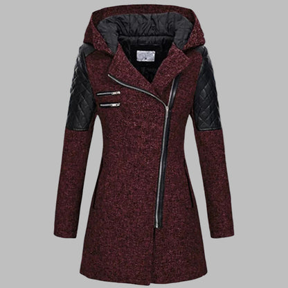 Donkerrode dames winterjas met capuchon, asymmetrische rits en zwarte leren accenten. Stijlvolle en warme jas voor koude winterdagen.
